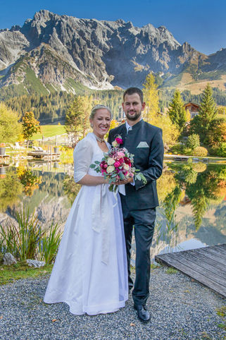 Brautpaar in Hochzeitsdirndl und Trachtenanzug am See