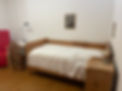 a bed in a cell with a desk and a chair next to it