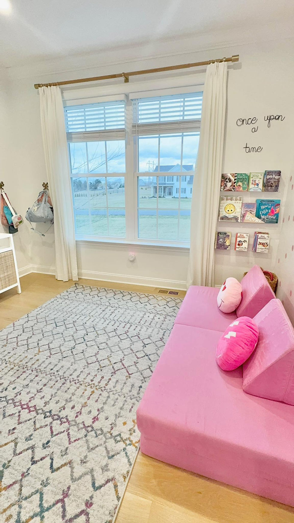 Bright and inviting children's playroom with a pink sofa, organized bookshelf, and playful decor, creating a cozy and structured space for imaginative play and storytime.