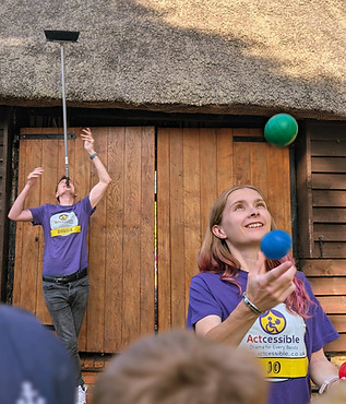 Two people juggling balls and balancing objects with Accessible logo on shirt.