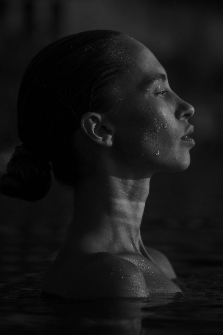 a fashion portrait of a young beautiful brunette woman in the lake enjoying the sunset