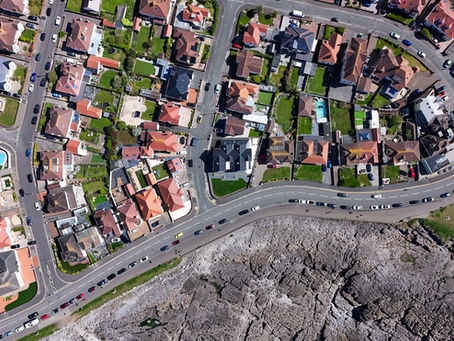 Aerial nadir shot of a seafront property, showcasing the home's footprint against a rugged, rocky coastline.