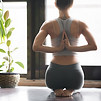 Young woman practicing yoga with namaste behind the back, sitting in seiza exercise, vajra