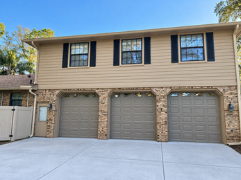 Three brown garage doors installed on a multi-bay residential property