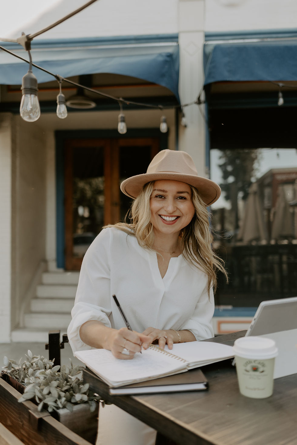 woman outside taking notes in a notebook at a table