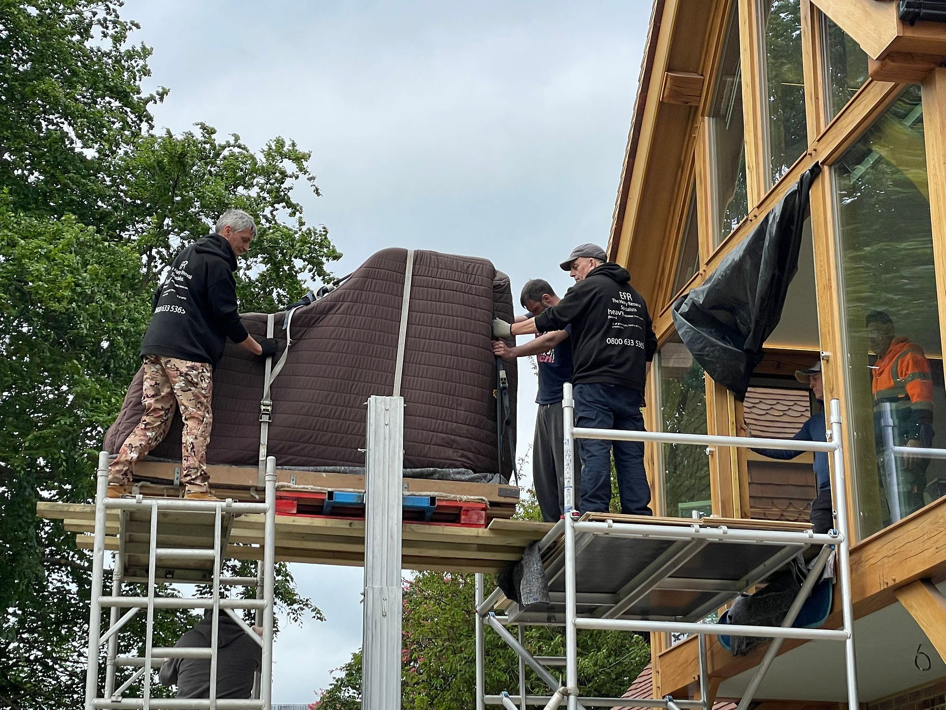 piano on a crane being lifted and moved into a house