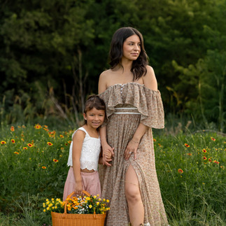 Cozy motherhood photography session in North Texas wildflowers with floral basket and candid moments between mother and daughter