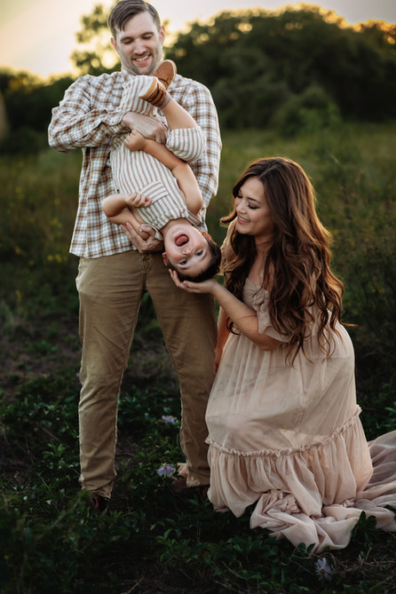 family of 3 having tons of fun with little boy hanging upside down laughing at murrell park in flower mound 