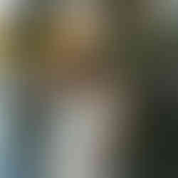 Woman in black dress and gloves poses with hand on head, eyes closed, in front of a stone wall, with sunlight highlighting her hair. Modeling session done at Adratica Village in Mckinney Texas by Precious Gems Photography