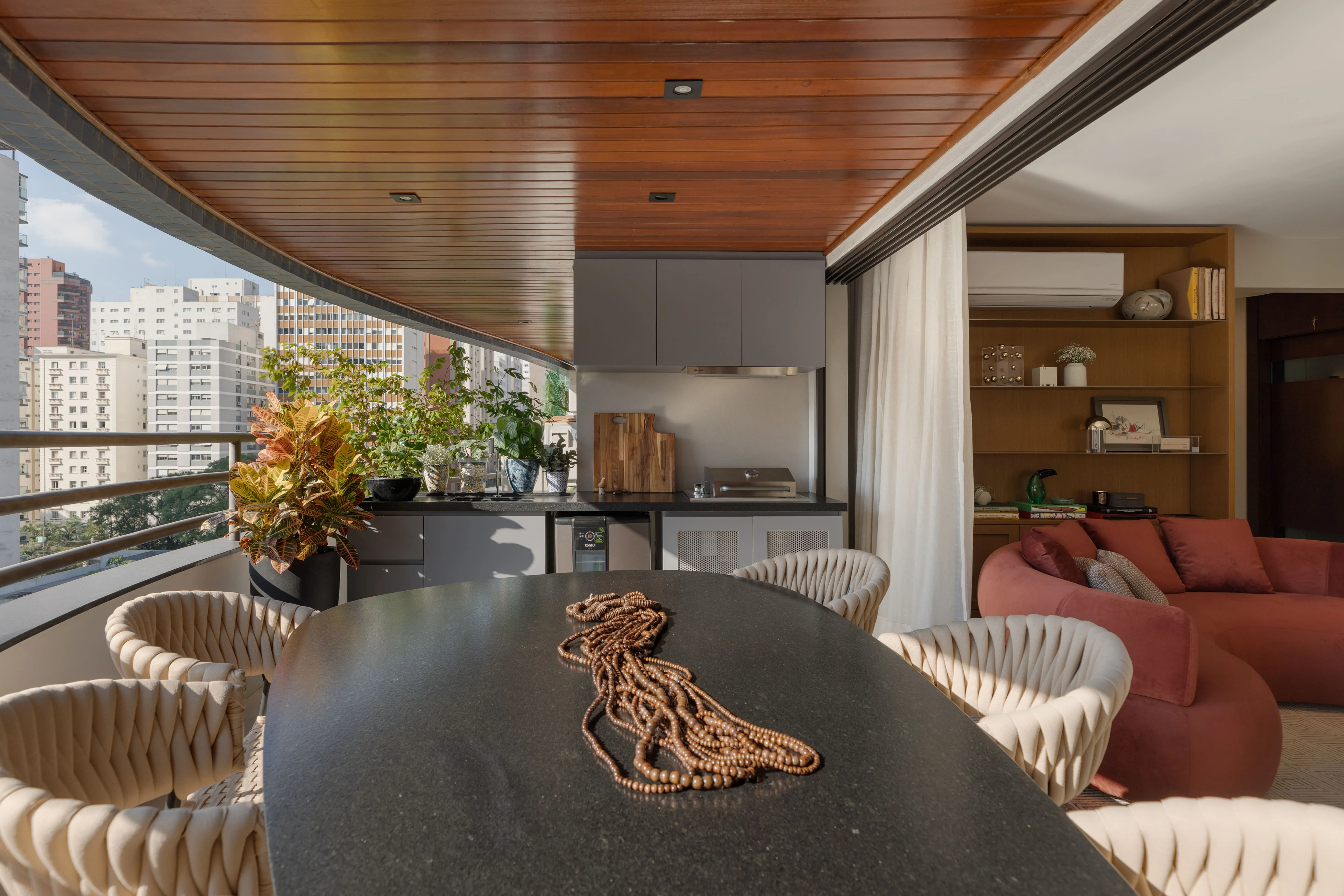 Detalhe de bancada curva em pedra com objeto decorativo, teto em madeira e ambiente interno aconchegante ao fundo.