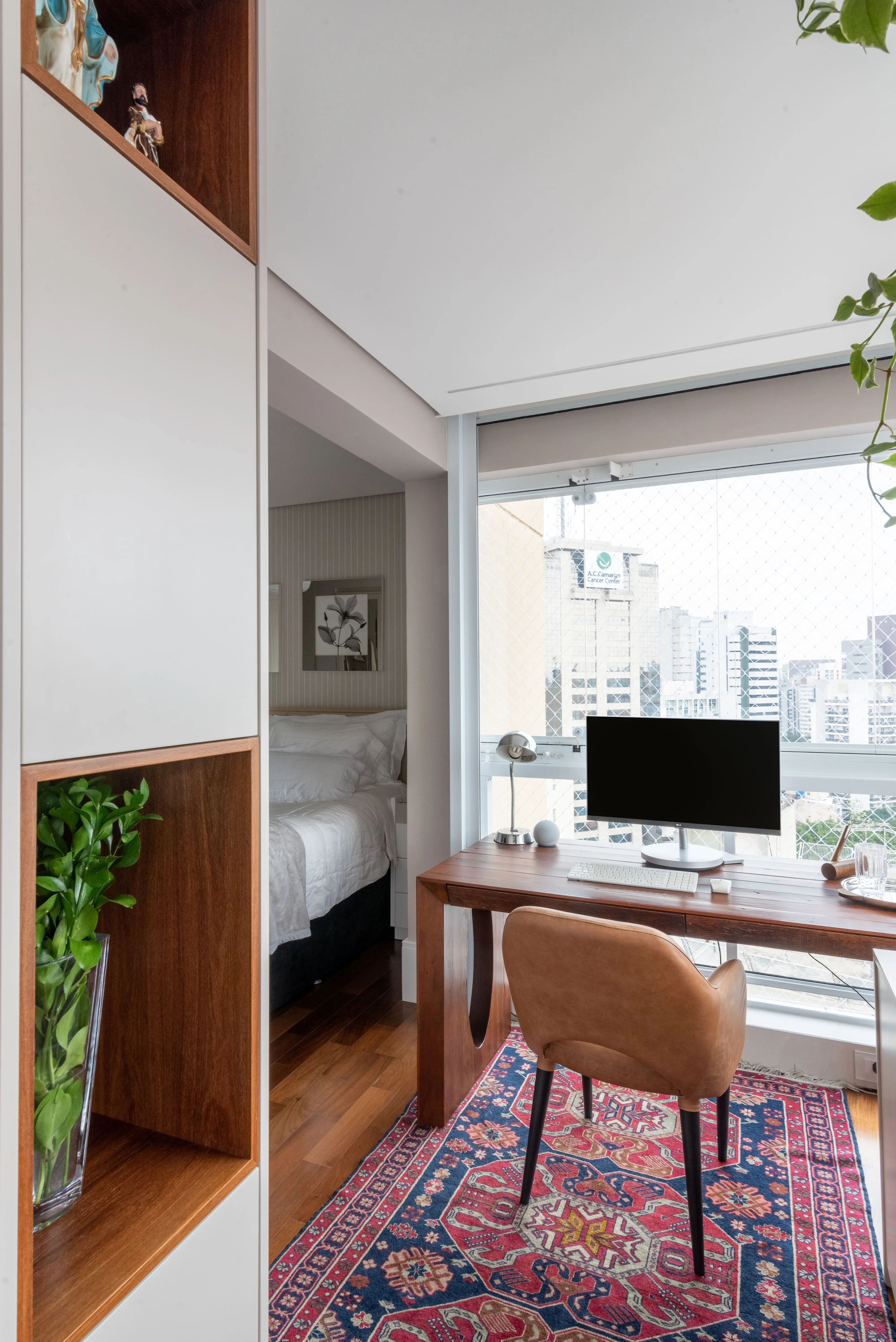 Home office com mesa de madeira próxima à janela, planta natural e iluminação abundante, criando um ambiente de trabalho leve e conectado à natureza.