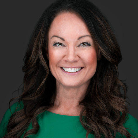 Professional headshot of a smiling woman with dark brown curly hair wearing a black top