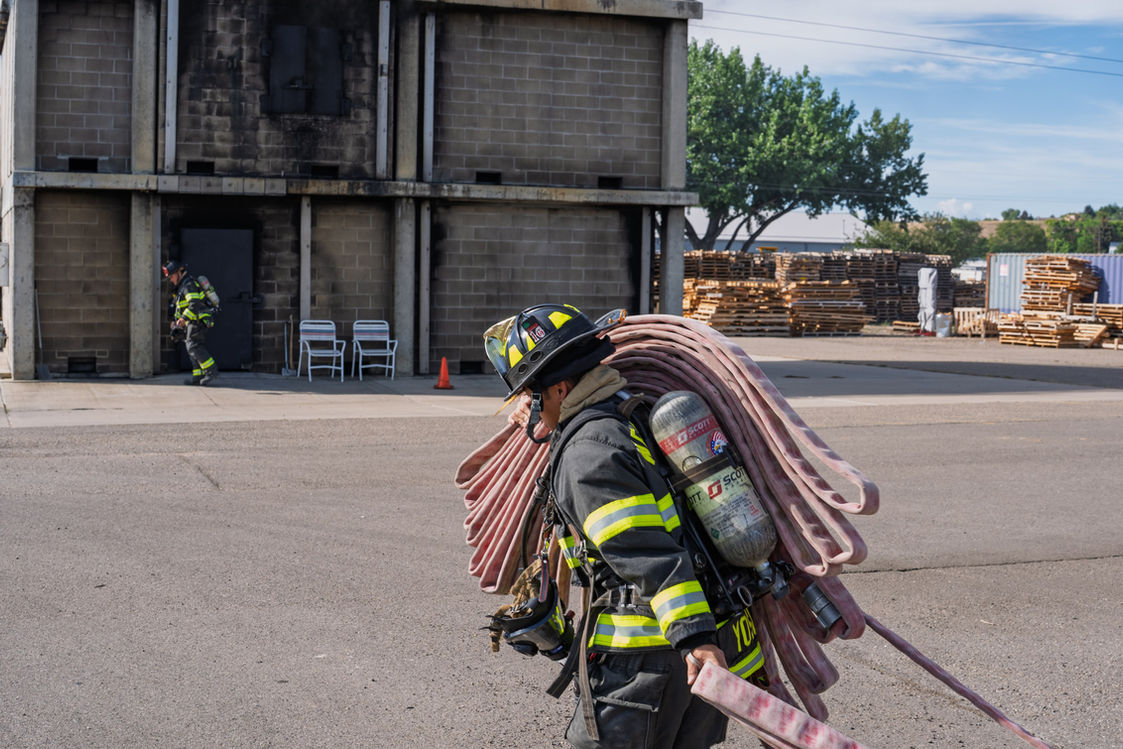 Wellington Firefighter carrying hose in a training scenario.