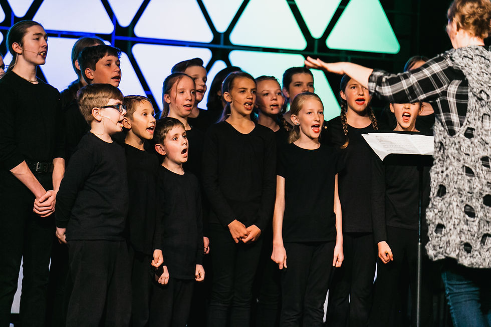 Choir teacher directs an ensemble of students in singing songs that are written by Marlene at Faith Based Student Musicals.
