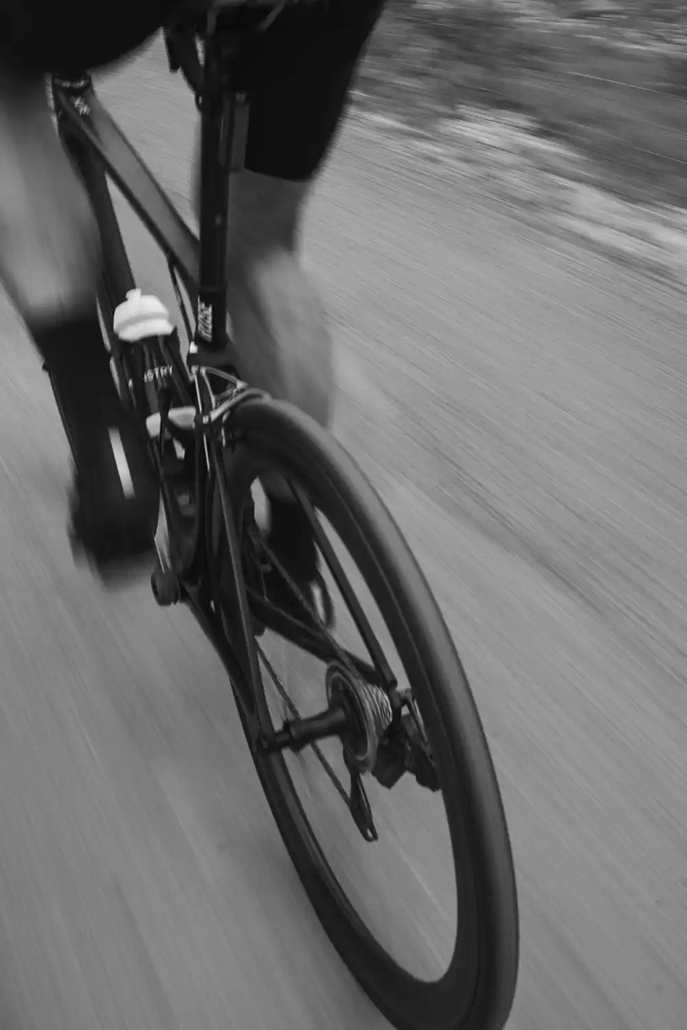 Rennradfahrer in schneller Fahrt, Schwarz-Weiß-Actionaufnahme von hinten.