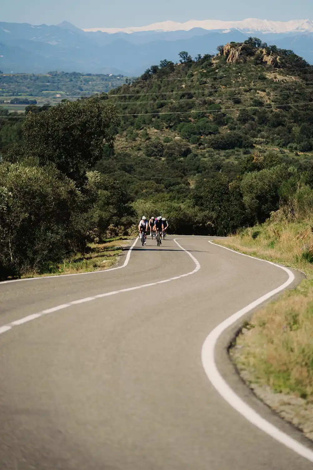 Bergige Straße in Girona mit einer Gruppe von Rennradfahrern