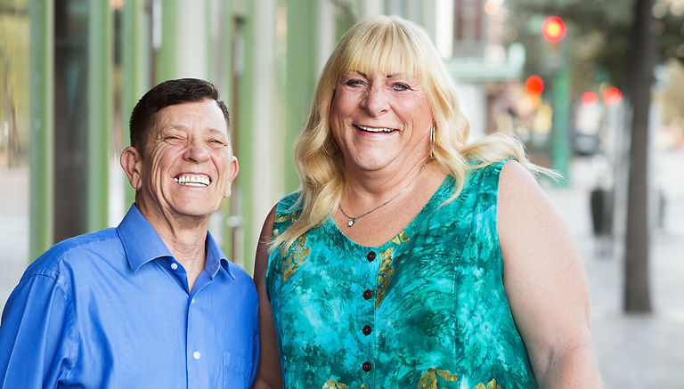 Two people smile toward the camera on a city street