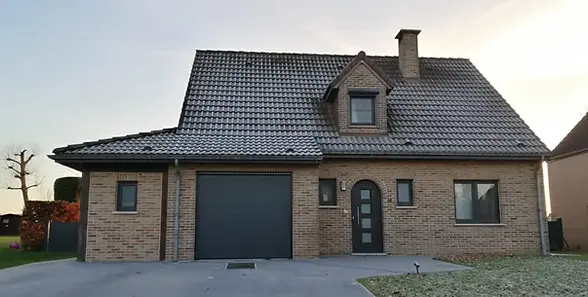Maison moderne en briques avec garage et lucarne.