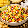 Bright bowl of mango pineapple salsa with diced mango, pineapple, red onion, cilantro, and lime. Tortilla chips on the side.