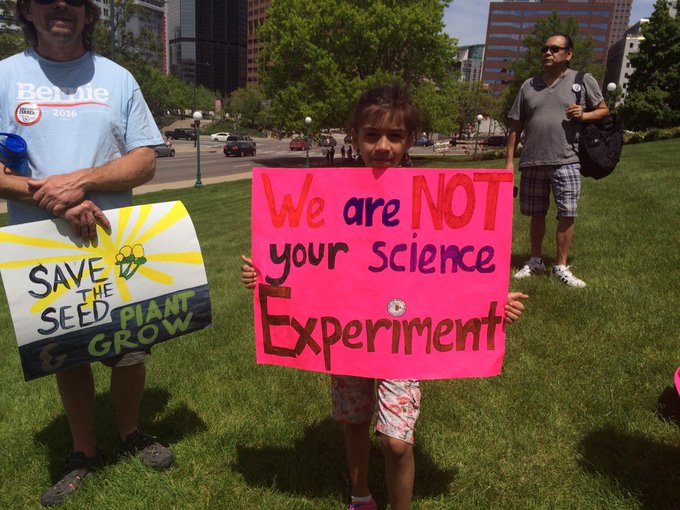 A foto mostra uma menina segurando um cartaz dizendo: Nós não somos o seu experimento de ciências.