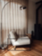 Fauteuil design en tissu beige à structure métallique noire, éclairé par une lampe sur pied chromée, dans un intérieur contem