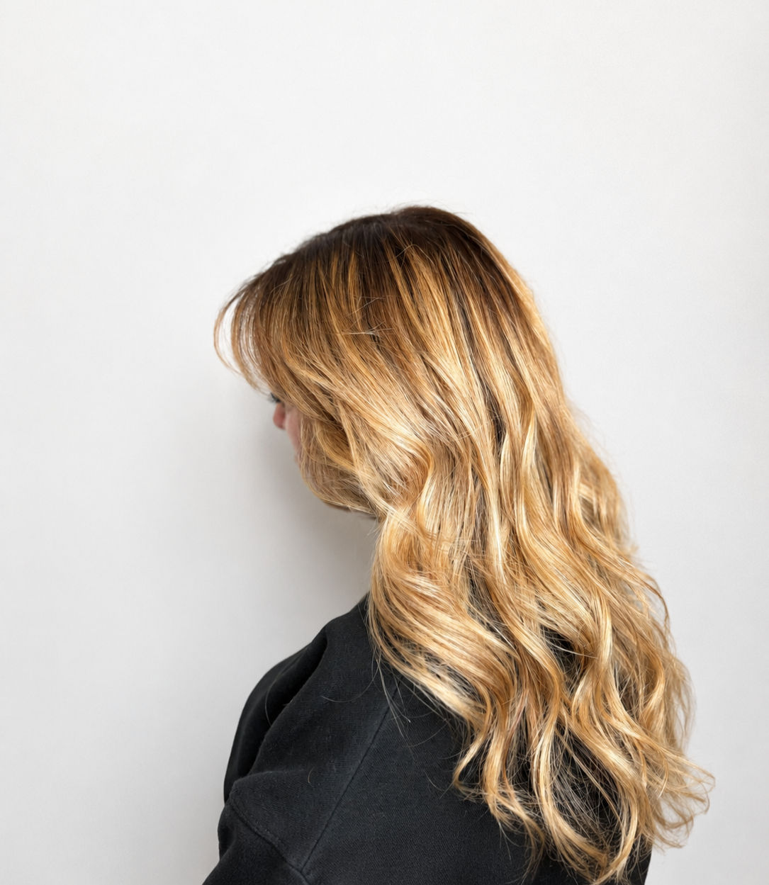 Client receiving a wash and blow dry in a hair salon, with the stylist creating soft, bouncy curls for a smooth and glamorous finish.