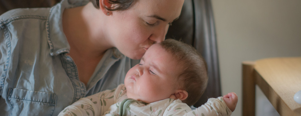 A family photoshoot in Austin area, a mother kisses her baby girl on the forehead in Manor, Texas.