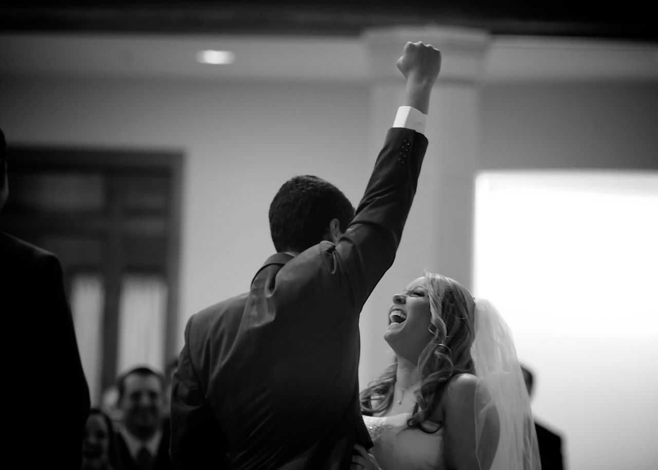 The groom lifts up his hand to celebrate getting married.