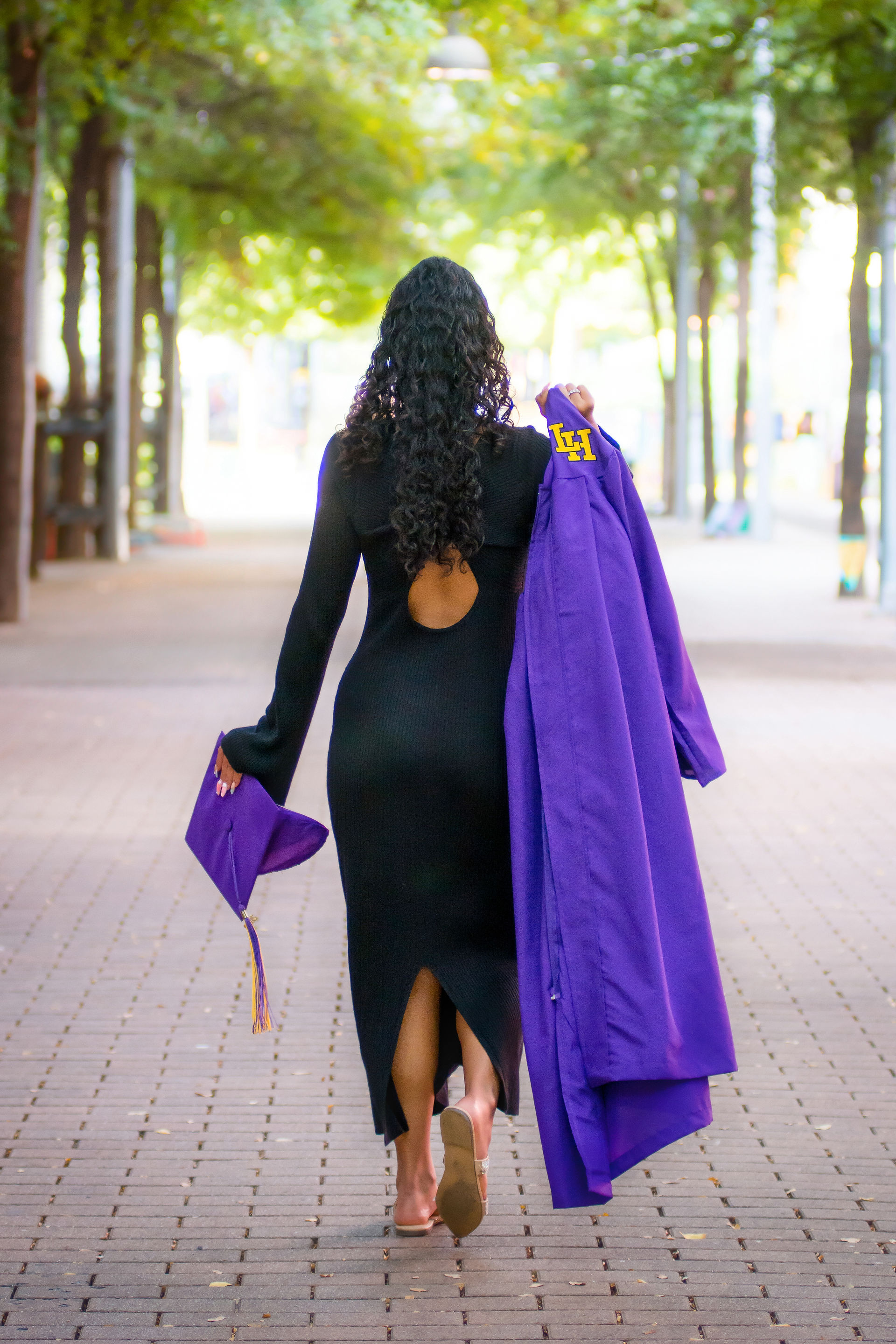 A Liberty Hill High School Senior walks into the distance holding her gown.