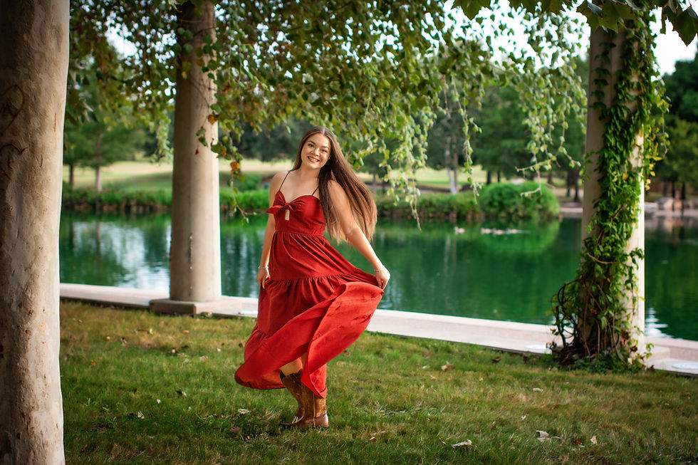 A senior girl spins in her red dress and cowgirl boots.