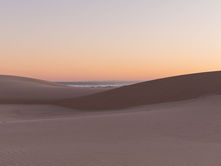 A photograph of a sand dune at sunset
