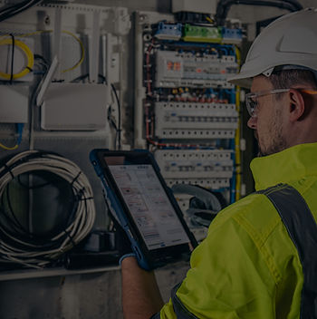 man-electrical-technician-working-switchboard-with-fuses-uses-tablet