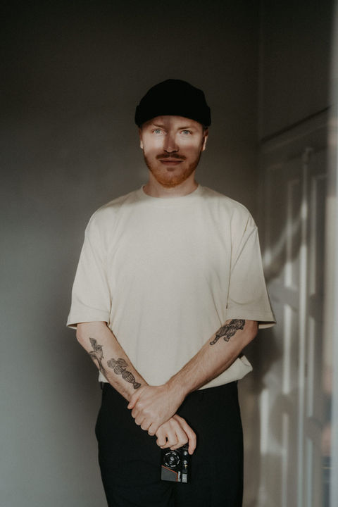 Porträt eines Mannes mit Mütze und Tattoos im warmen Licht.