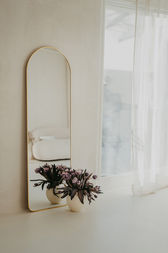 Eleganter goldener Standspiegel im Studio, dekoriert mit Blumen und weißen Tüchern.