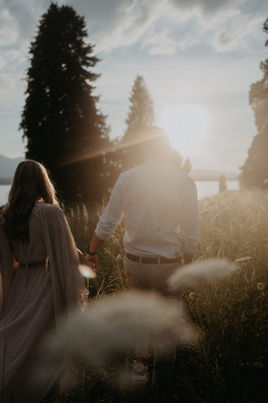 Paar geht durch eine sonnendurchflutete Wiese im Abendlicht.