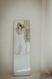 Fotografin vor hellem Studio-Setting im Standspiegel reflektiert – modernes Portrait.