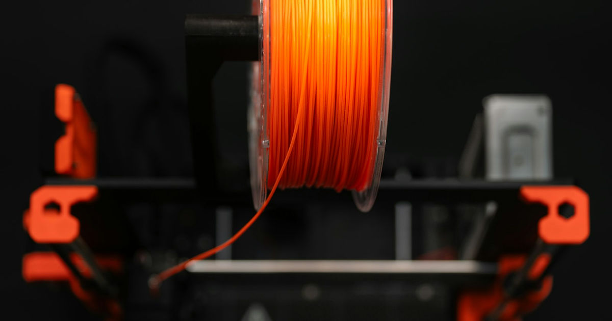 Orangefarbene Filamentspule an einem 3D-Drucker
