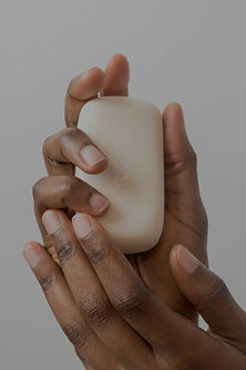 Two hands are posed holding a bar of handmade soap