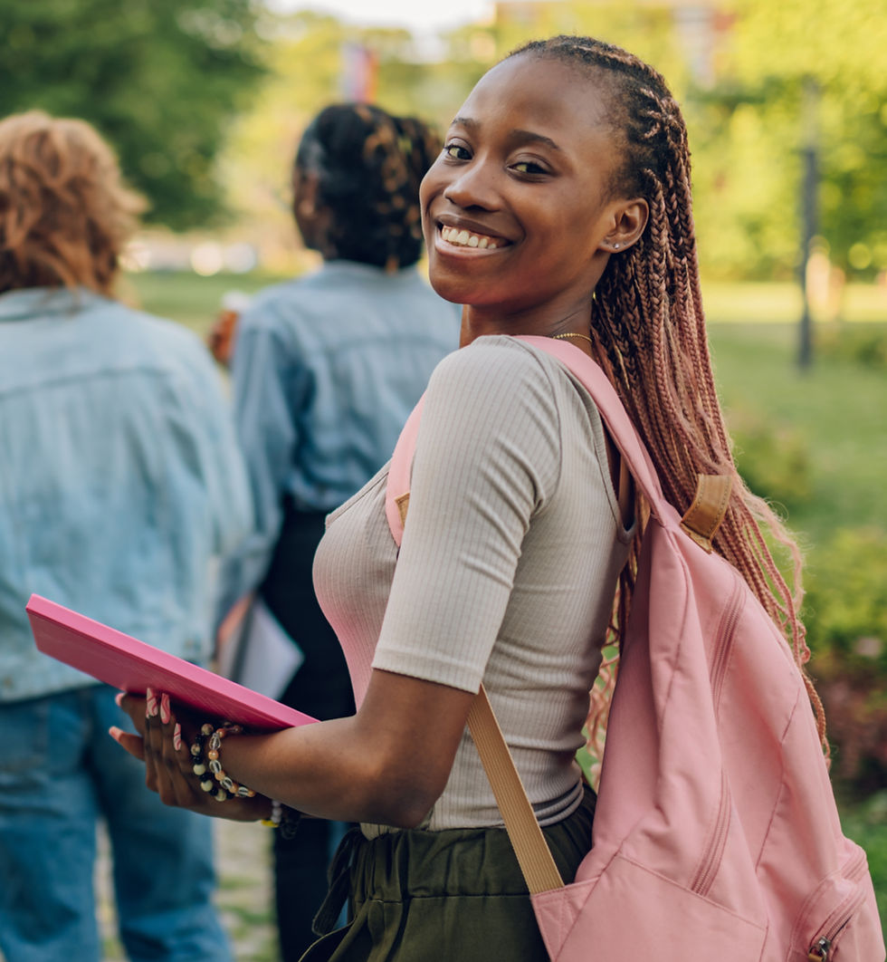 Portrait of multicultural female university student standing at campus near college buildi