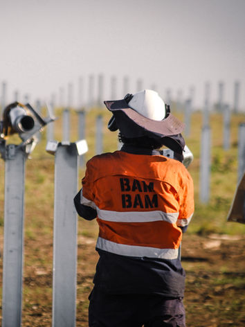 A worker inspects a row of piles on a solar farm