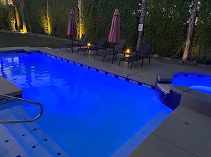 LUXOASIS custom pool with blue LED lighting and water features at night in the Coachella Valley