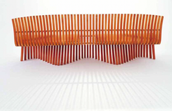 Wooden bench with vertical slats and wave-like base, shadows. Diamond Tropical Hardwoods