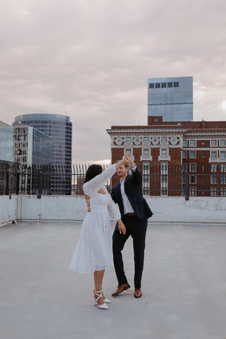 couple in suit and dress dancing on a garage rooftop in Grand Rapids. You can see the JW marriot, amway historical building, and a nice sunset behind them.