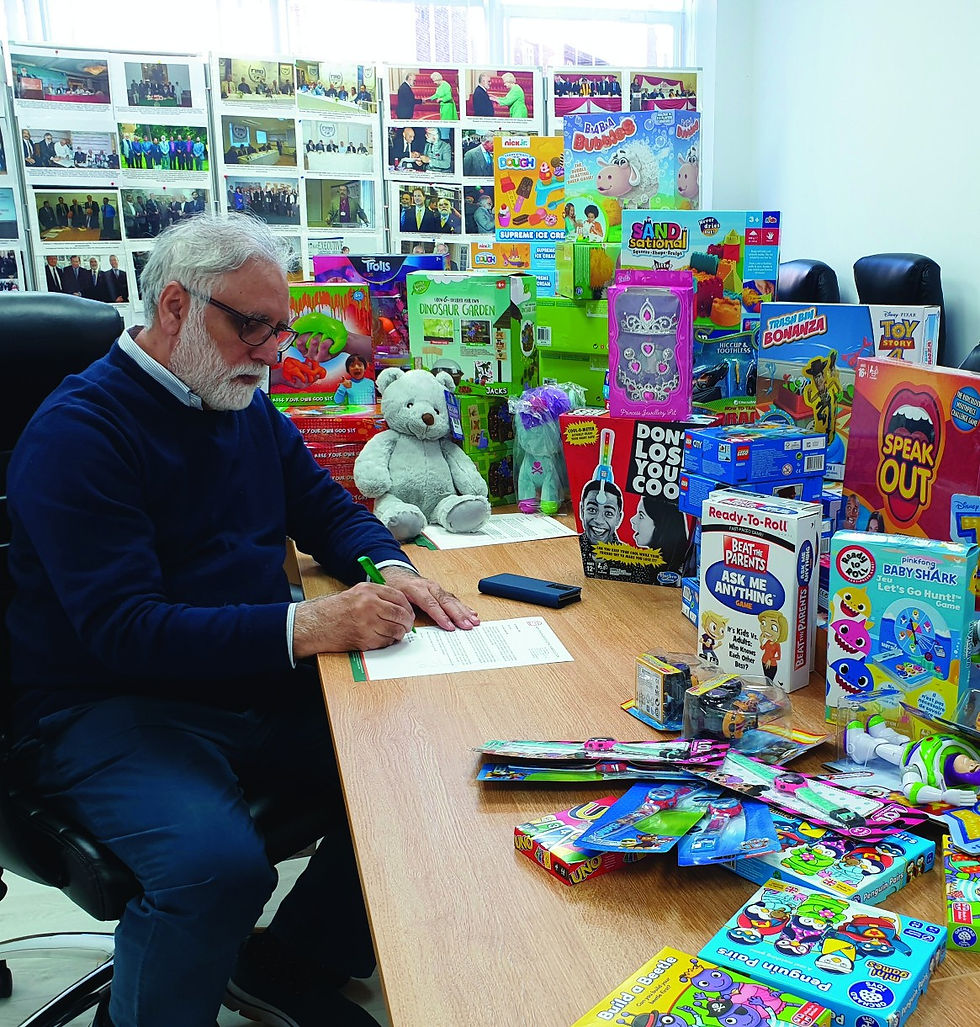 Toaha Qureshi MBE, CEO, signs a letter for toys being delivered to children in London and the Midlands.