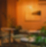 Warmly lit modern café interior with rattan chairs, wooden accents, and minimalist abstract painting