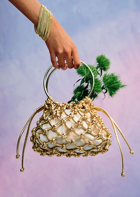 Hand holding golden bag with green flowers