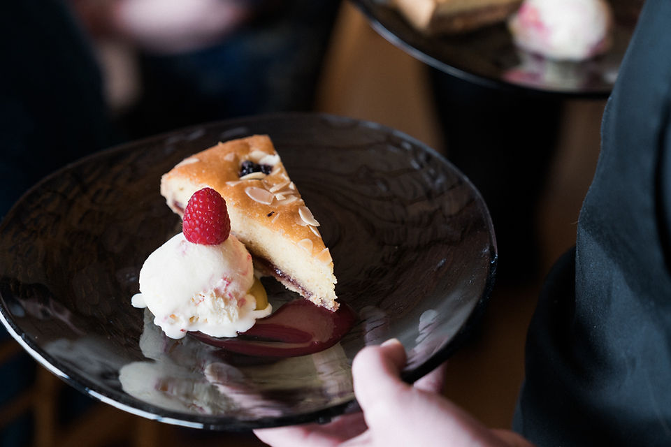 Bakewell pudding dessert at Dodford Manor with ball of ice cream and a raspberry on top, being carried by a waitress in black.