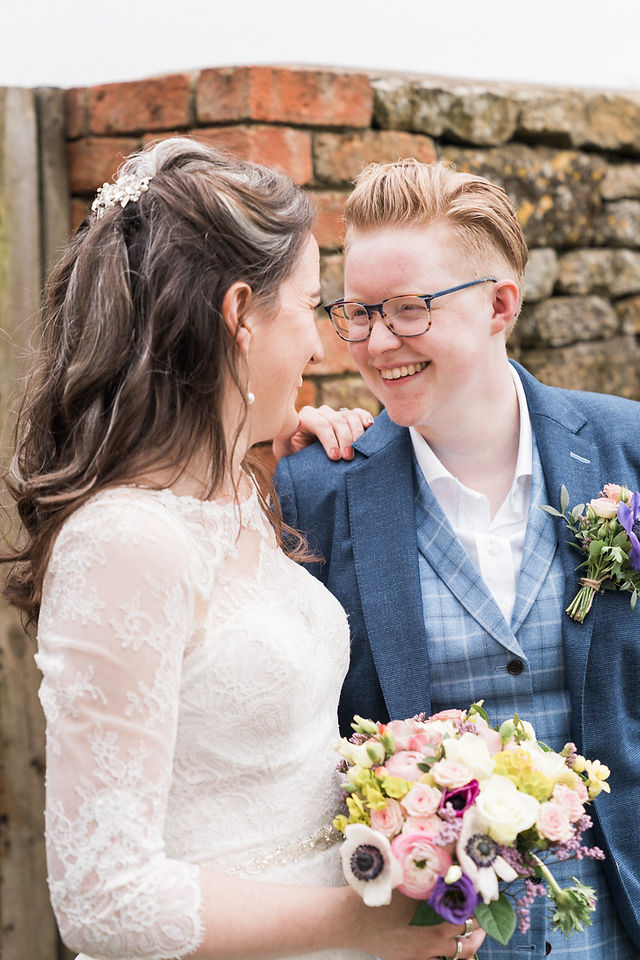 The best wedding photography at Dodford Manor. Gay couple wedding photo making each other laugh outside in front of a wooden gate. Natural wedding photography. Leicester wedding photographer. Covering wedding photography in Rutland, Derbyshire, Northamptonshire, Lincolnshire, Darley and Underwood Photography.