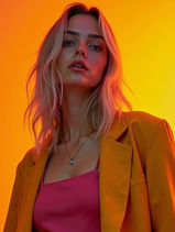 Creative fashion portrait of a woman wearing a mustard blazer against a vibrant orange background