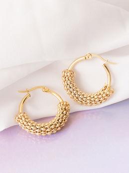 Creative product photograph of gold hoop earrings on soft white and pastel fabric